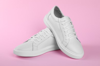 Photo of Pair of stylish white sneakers on pink background