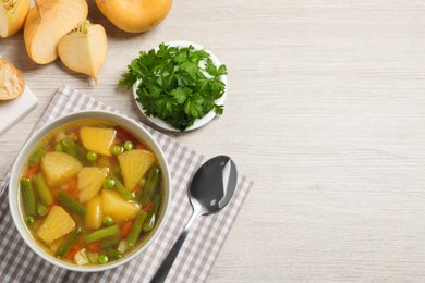 Bowl of delicious turnip soup served on wooden table, flat lay. Space for text