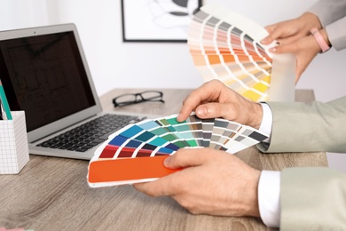 Team of designers working with color palettes at office table, closeup