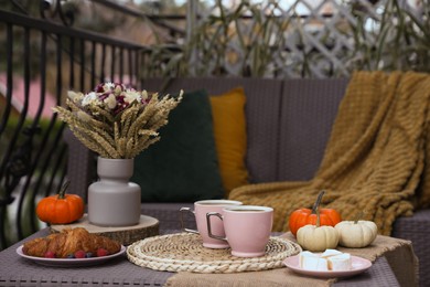 Photo of Rest on terrace with rattan furniture. Drink, dessert and autumn decor on table