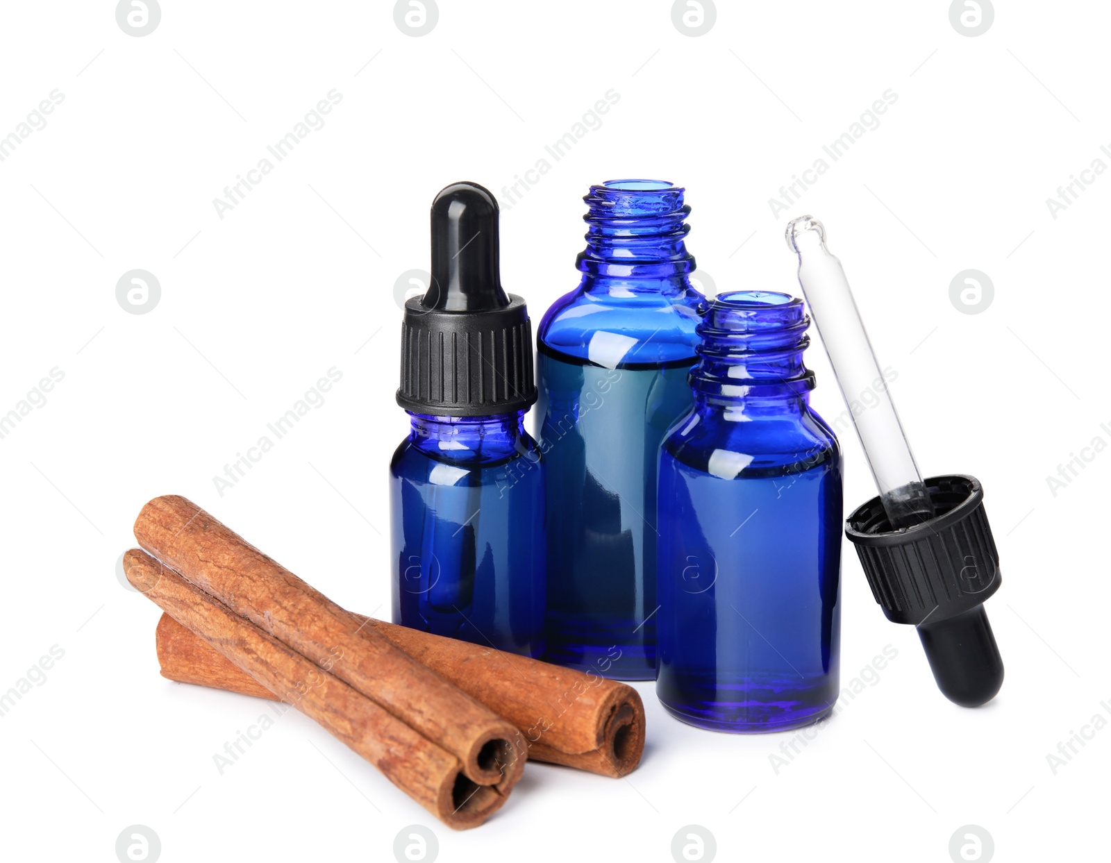 Photo of Bottles of essential oils and cinnamon sticks on white background