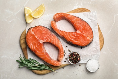 Photo of Fresh salmon steaks with spices, lemon and rosemary on marble table, top view