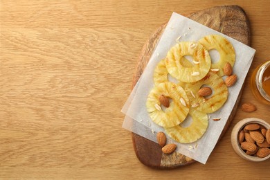 Tasty grilled pineapple slices and almonds on wooden table, flat lay. Space for text