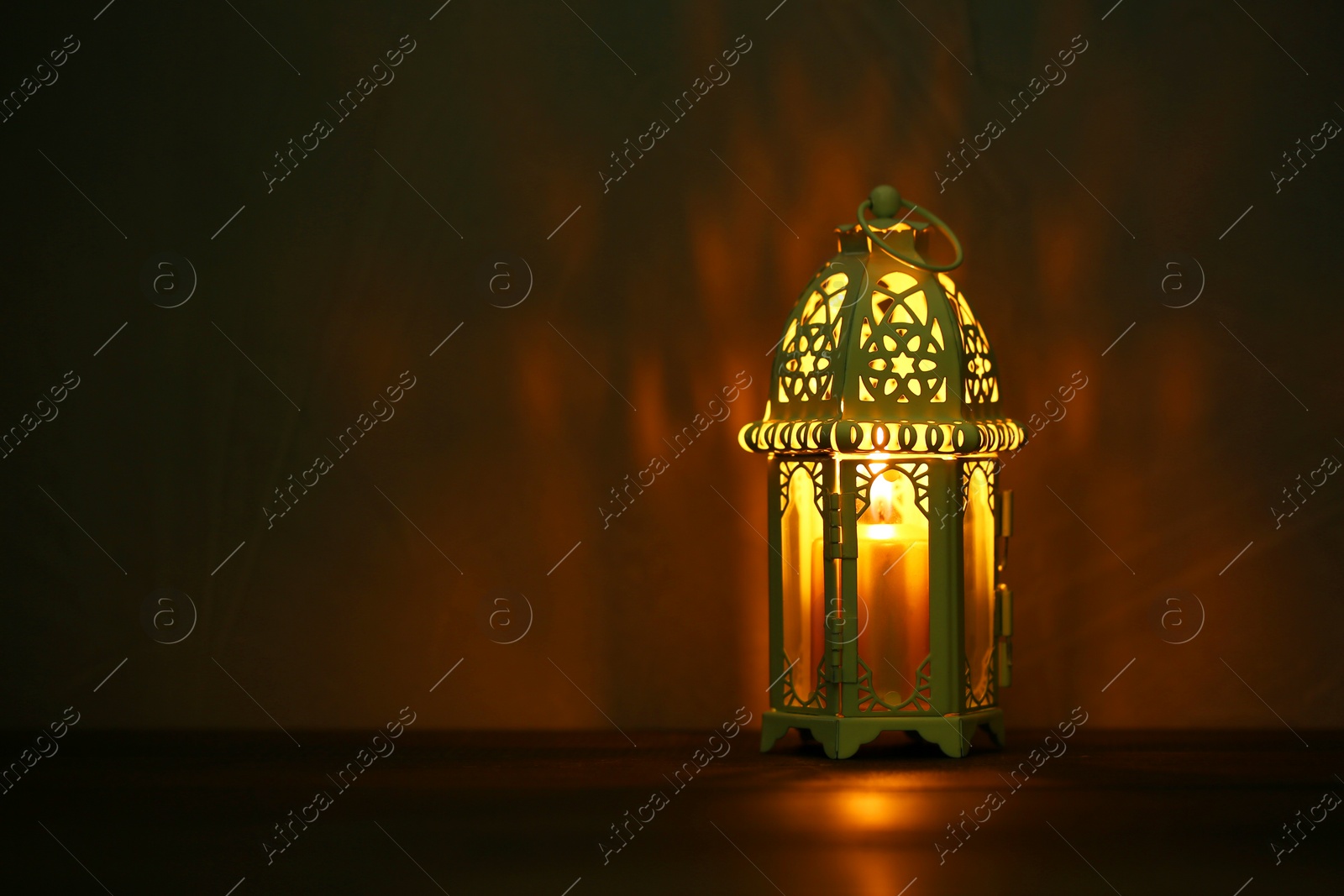 Photo of Decorative Arabic lantern on table against dark background. Space for text