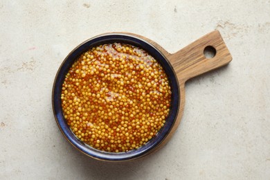 Whole grain mustard in bowl on light table, top view