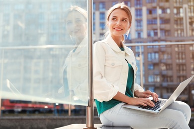 Photo of Beautiful woman with laptop on city street