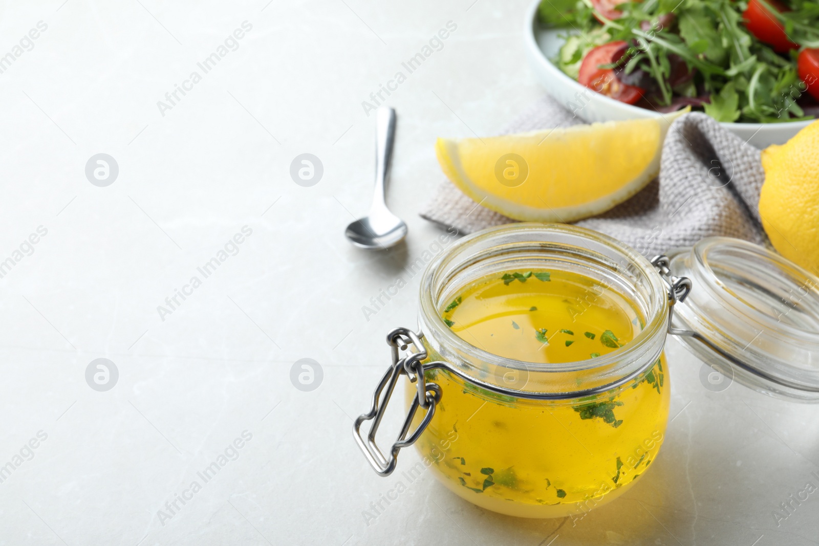 Photo of Jar with lemon sauce on light table, space for text. Delicious salad dressing