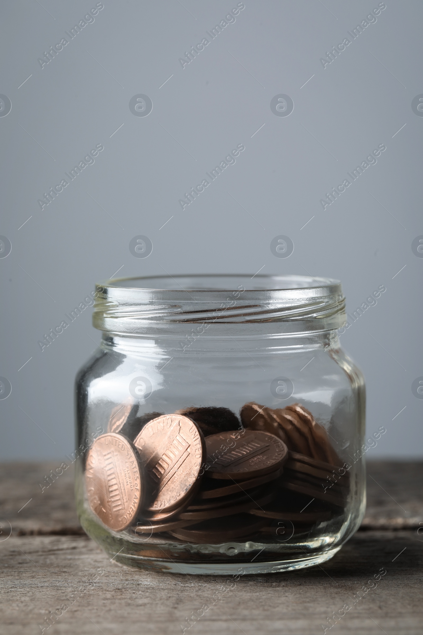 Photo of Glass jar with coins on wooden table, closeup