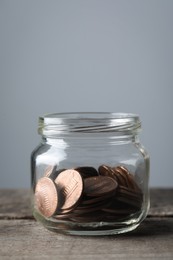 Photo of Glass jar with coins on wooden table, closeup