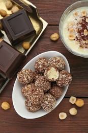Photo of Delicious sweet chocolate candies and ingredients on wooden table, flat lay