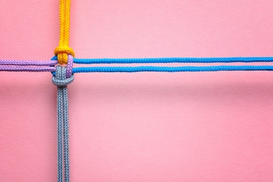 Different ropes tied together with knot on color background. Unity concept