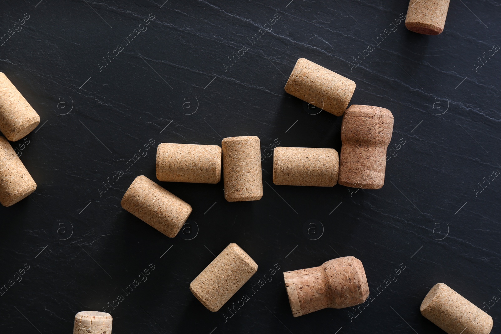 Photo of Wine bottle corks on black table, flat lay