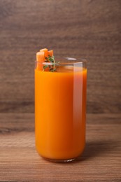 Fresh carrot juice in glass on wooden table
