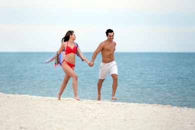 Happy young couple running together on sea beach