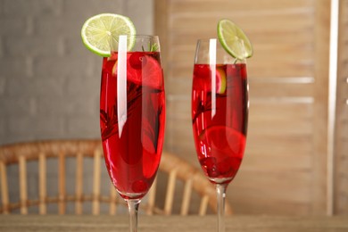 Photo of Tasty cranberry cocktail with rosemary and lime in glasses indoors, closeup