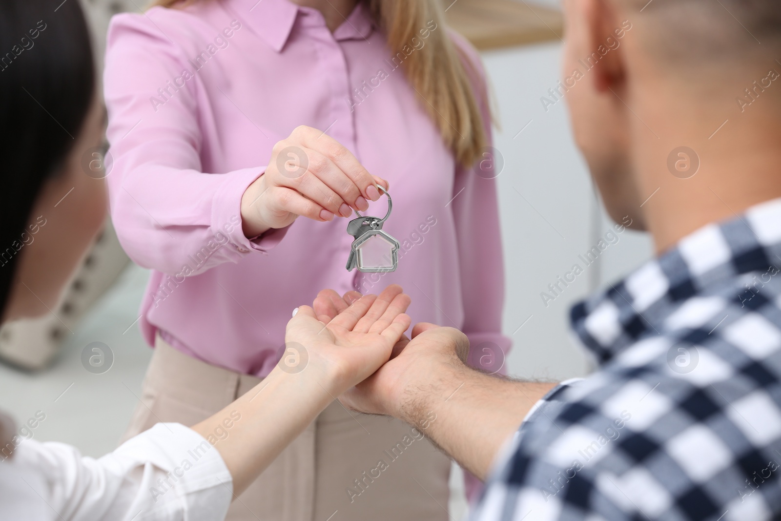 Photo of Real estate agent giving house key to couple, closeup