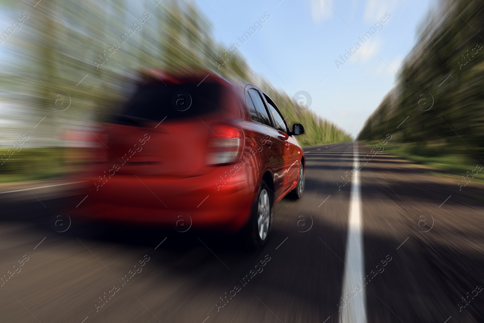 Image of Red car driving at high speed on asphalt road outdoors, motion blur effect