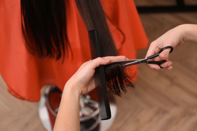 Stylist cutting hair of client in professional salon, closeup