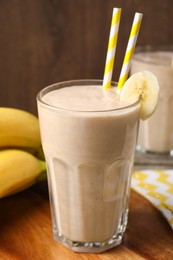 Glass with banana smoothie on wooden table