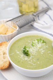 Photo of Delicious broccoli cream soup with cheese served on white table, closeup. Space for text