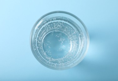 Photo of Glass of soda water on light blue background, top view