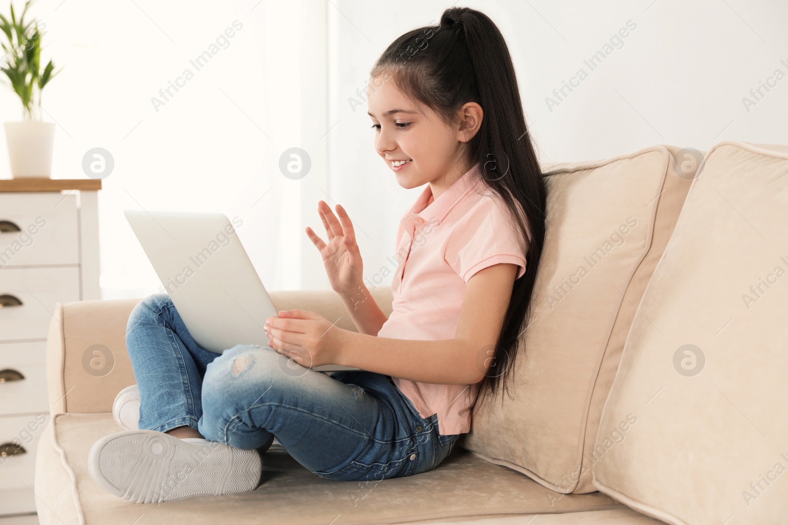 Photo of Little girl using video chat on laptop at home