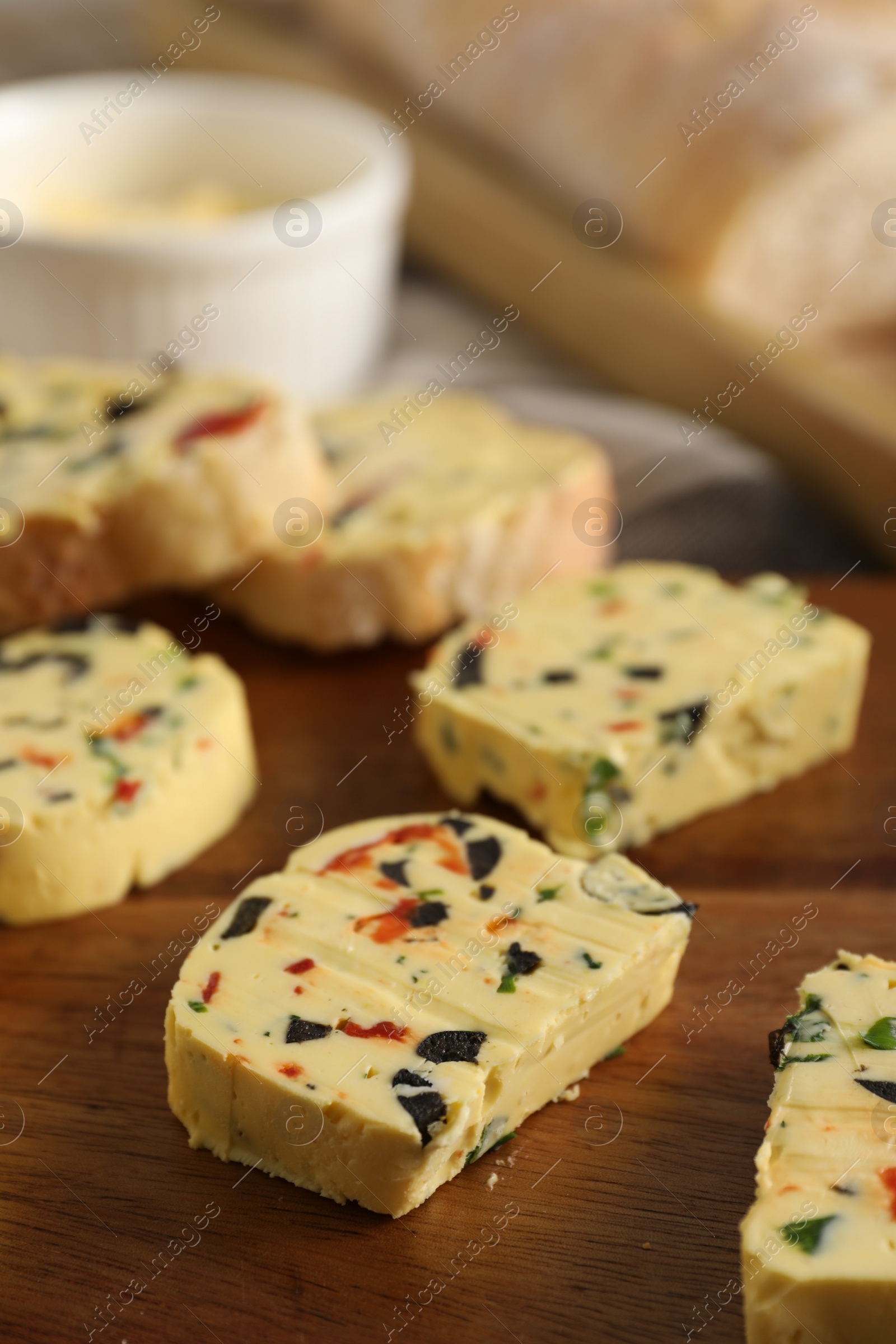 Photo of Tasty butter with olives, chili pepper, parsley and bread on table, closeup