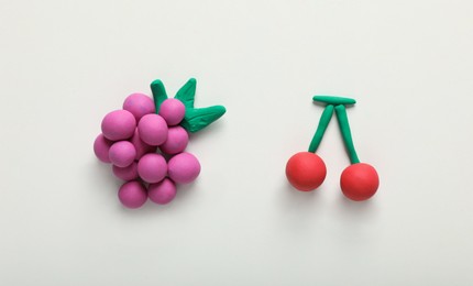 Colorful grapes and cherry made from plasticine on white background, top view