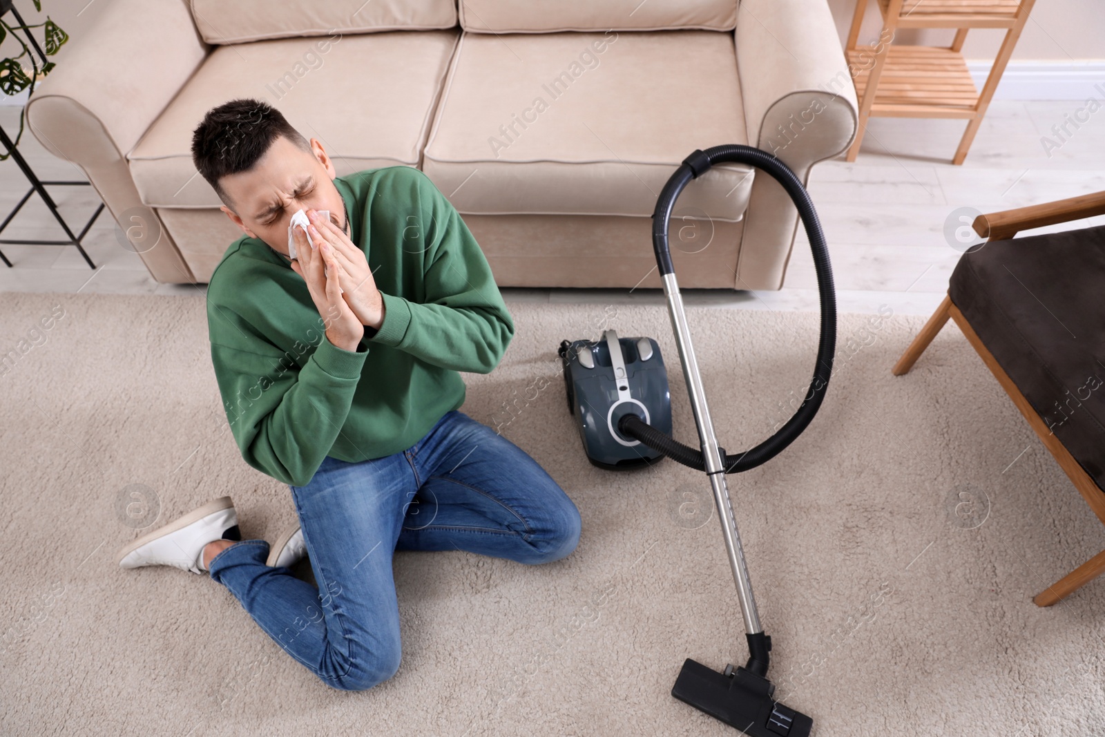 Photo of Man with vacuum cleaner suffering from dust allergy at home, above view