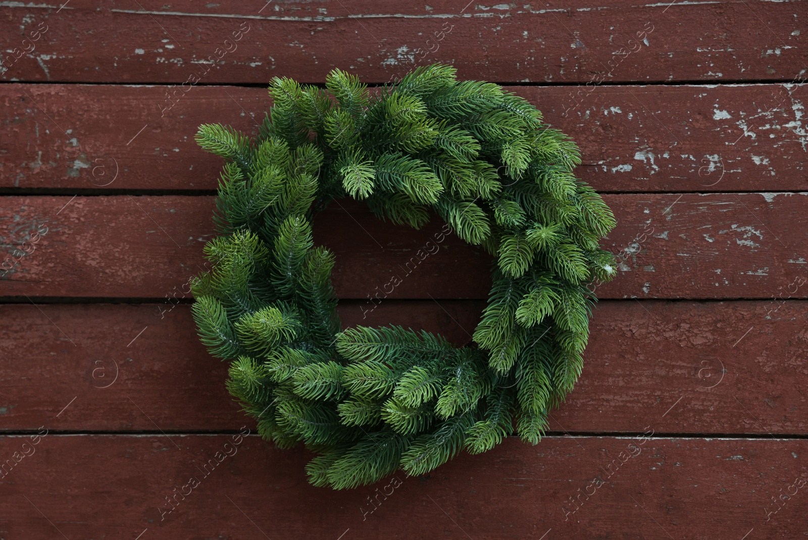 Photo of Beautiful Christmas wreath hanging on brown wooden wall