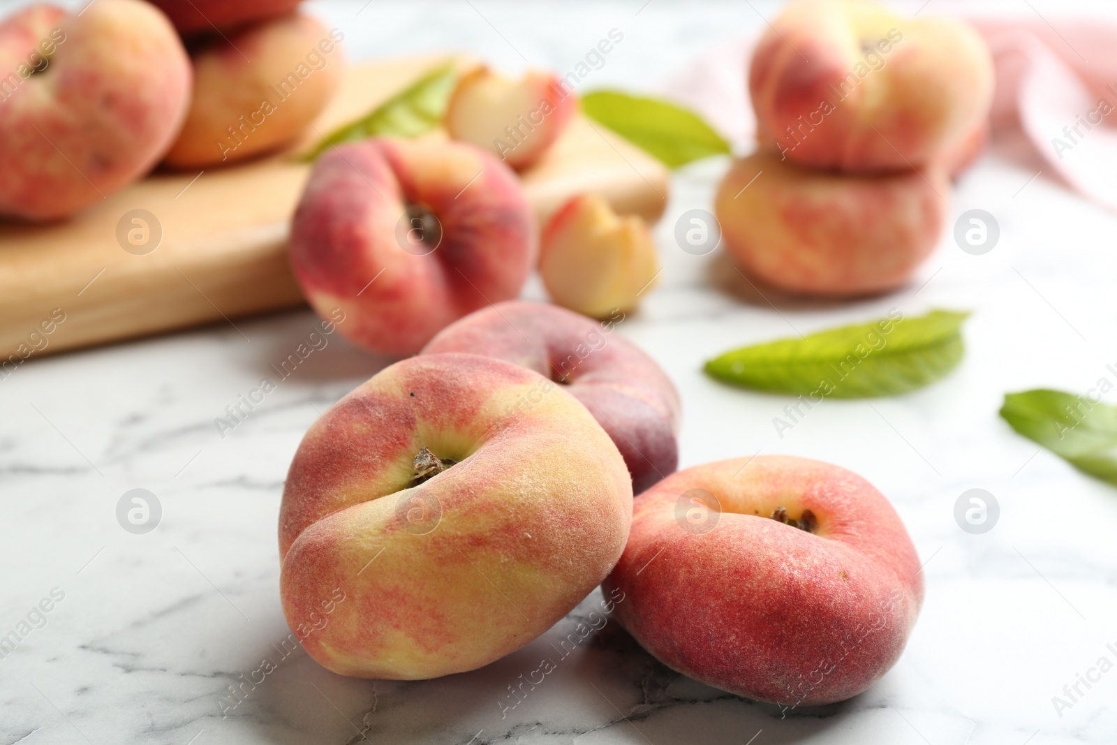 Photo of Fresh ripe donut peaches on white marble table, closeup