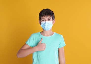 Photo of Boy wearing protective mask on yellow background, space for text. Child safety