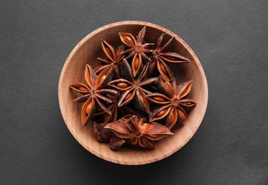 Photo of Aromatic anise stars in wooden bowl on grey background, top view