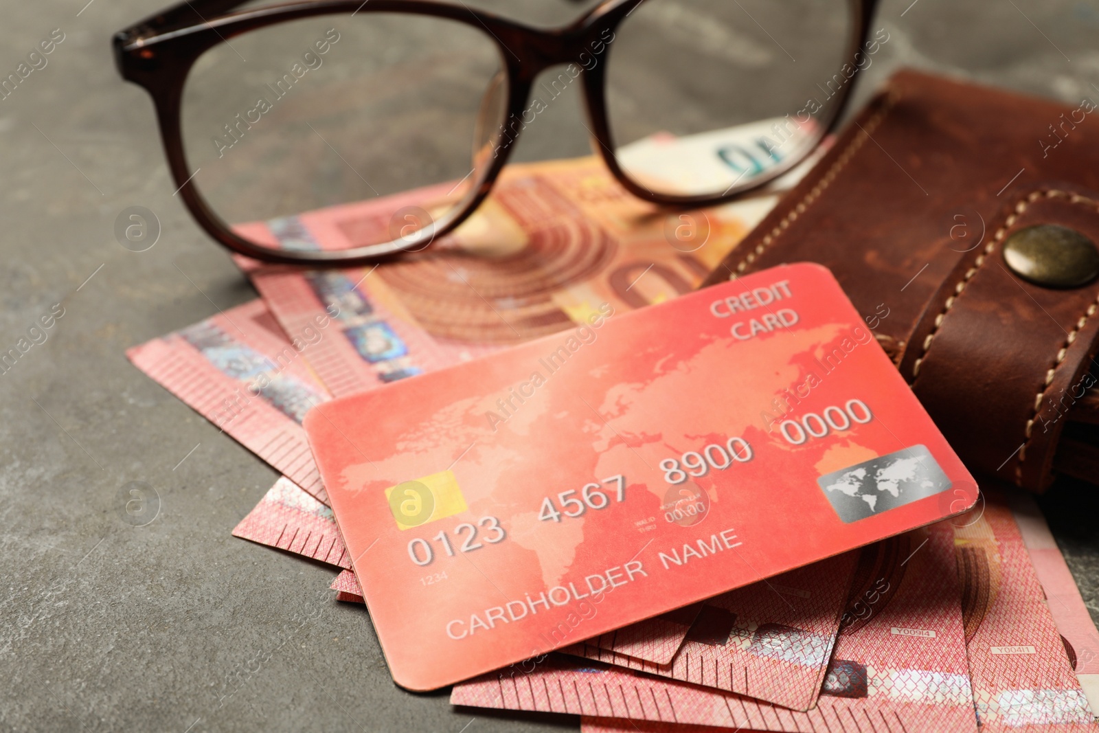 Photo of Credit card, wallet, money and glasses on grey table, closeup