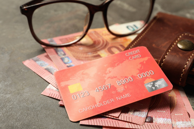Photo of Credit card, wallet, money and glasses on grey table, closeup