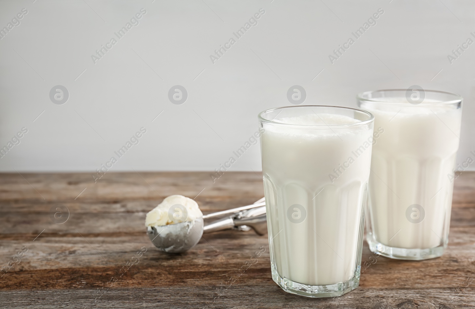 Photo of Glasses with milkshake and tasty vanilla ice cream on wooden table