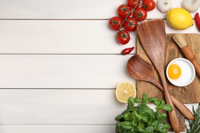 Flat lay composition with cooking utensils and fresh ingredients on white wooden table. Space for text