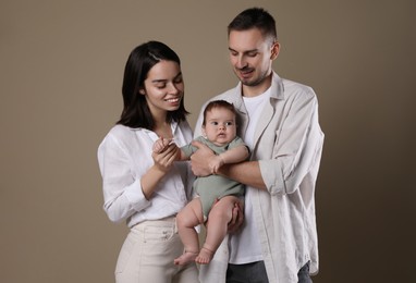 Happy family. Couple with their cute baby on beige background