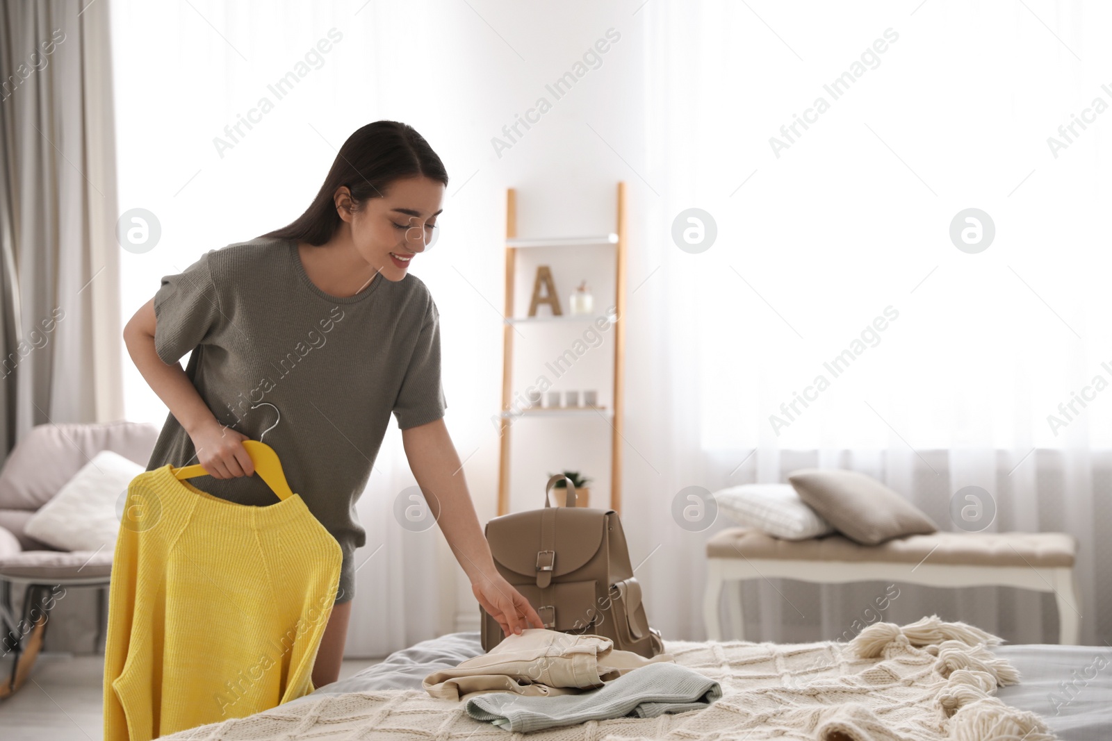 Photo of Young woman choosing clothes for work day at home. Morning routine