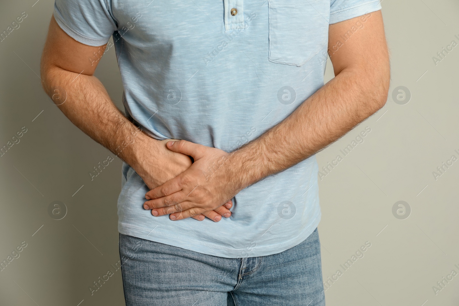 Photo of Man suffering from acute appendicitis on light grey background, closeup
