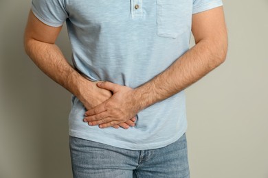 Man suffering from acute appendicitis on light grey background, closeup