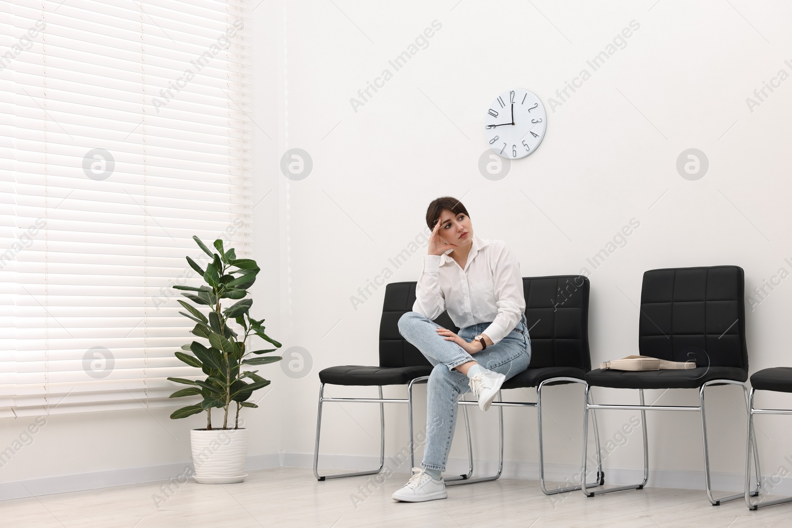 Photo of Woman sitting on chair and waiting for appointment indoors