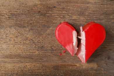 Photo of Broken heart shaped soap bar on wooden background, top view with space for text. Relationship problems concept