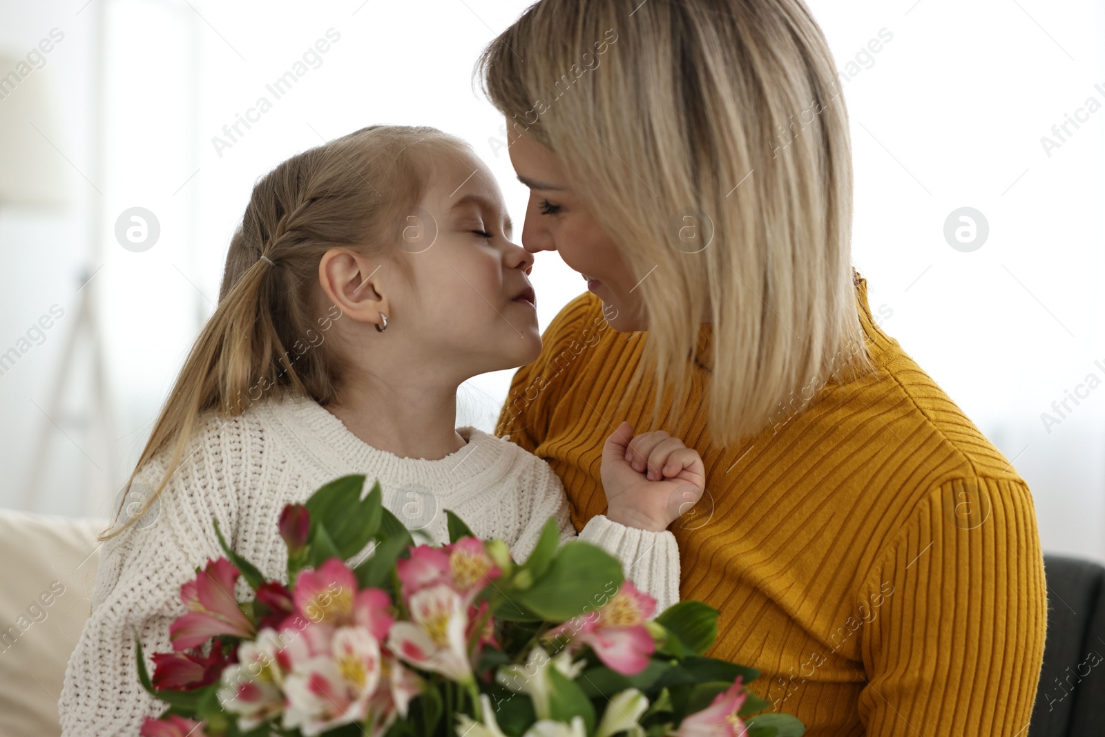 Photo of Little daughter congratulating her mom with bouquet of alstroemeria flowers at home. Happy Mother's Day