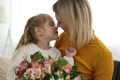 Photo of Little daughter congratulating her mom with bouquet of alstroemeria flowers at home. Happy Mother's Day