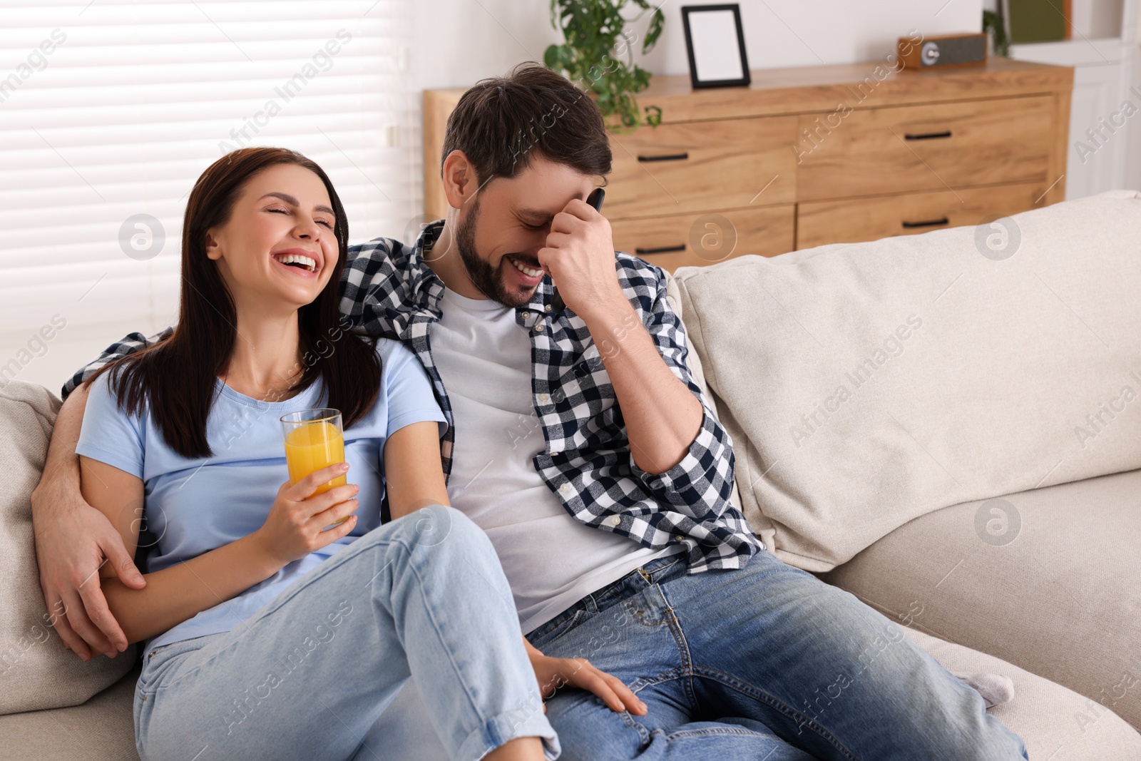 Photo of Couple watching comedy via TV and laughing at home