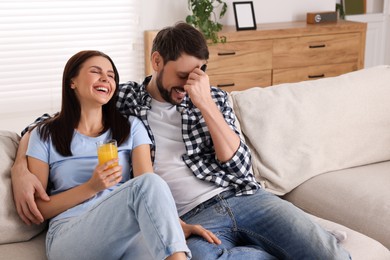 Couple watching comedy via TV and laughing at home