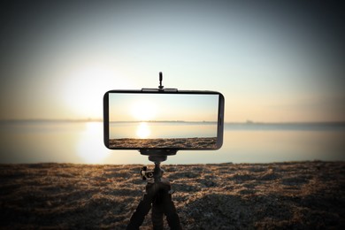 Image of Taking photo of beautiful seascape with smartphone mounted on tripod