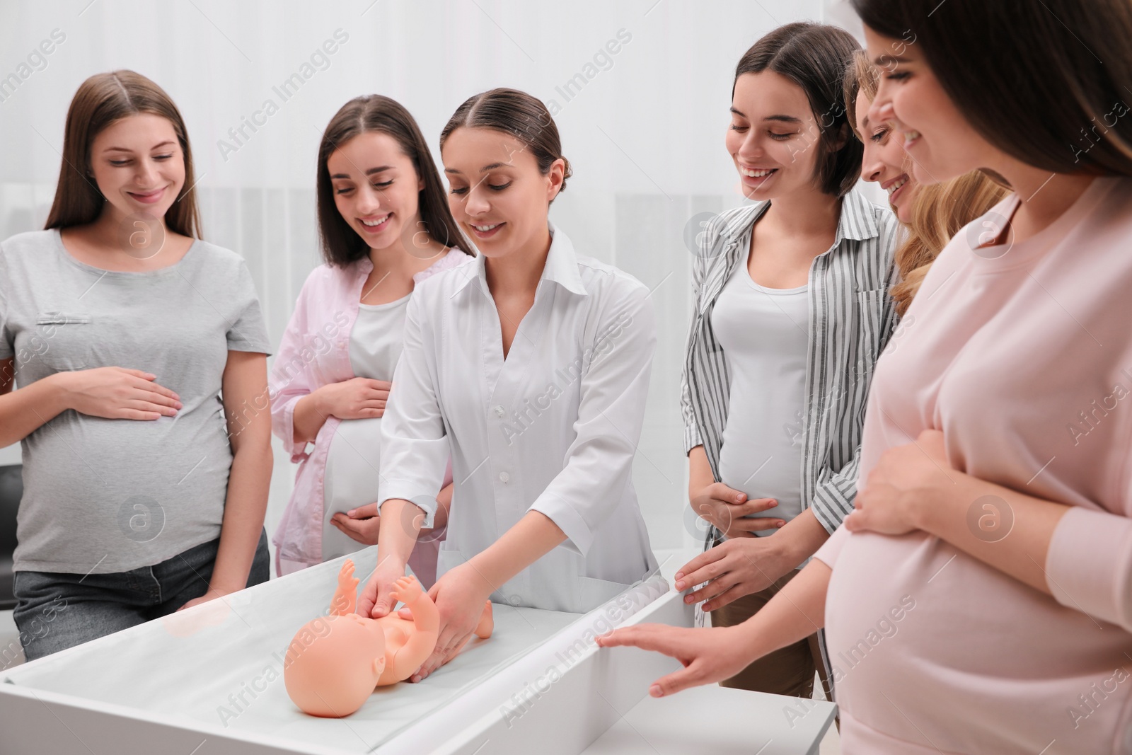 Photo of Pregnant women learning how to swaddle baby at courses for expectant mothers indoors