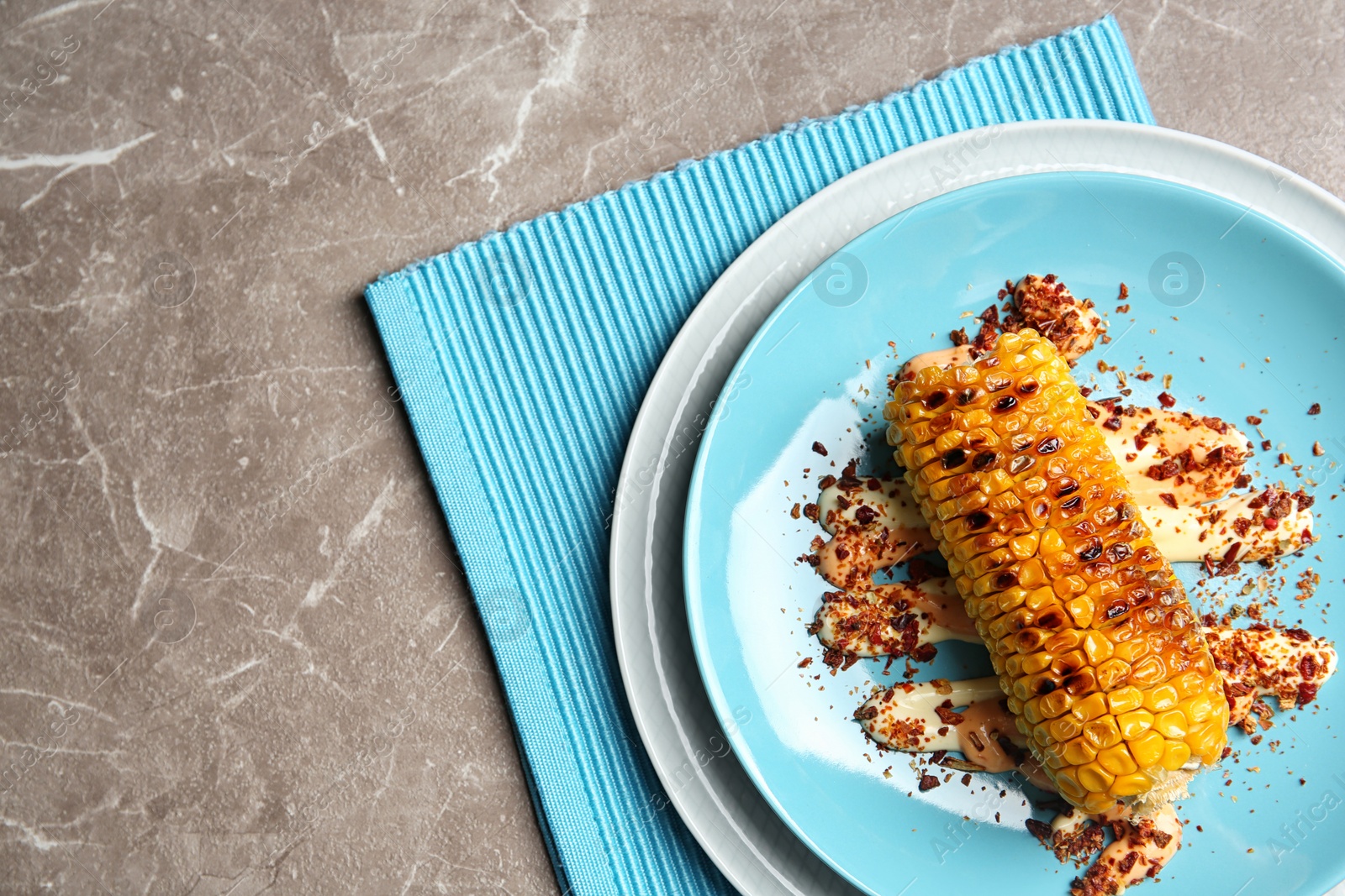 Photo of Plate with delicious grilled corn cob and spices on table, top view